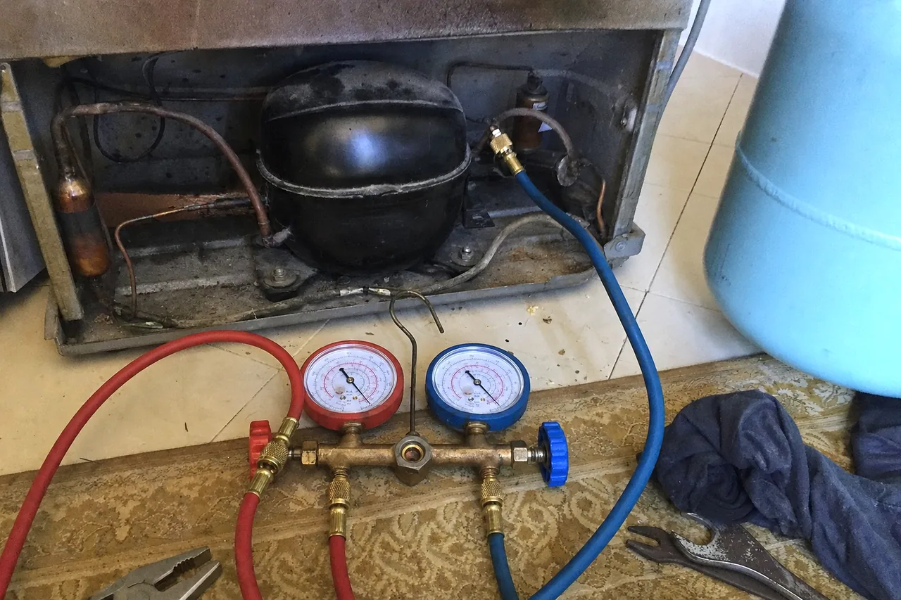 A gauge manifold and its hoses laid out in front of an open machine compartment, mirrored so the cylinder stands to the right.