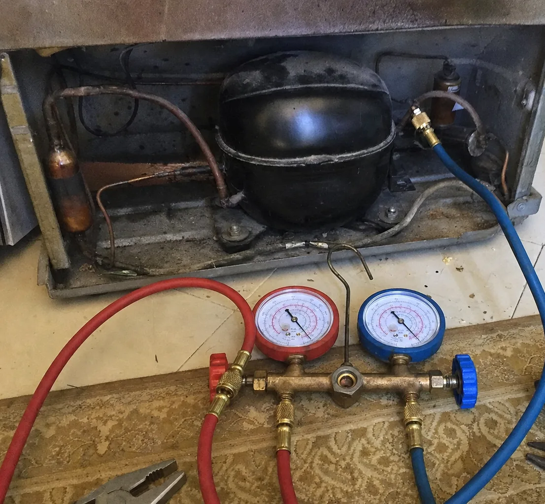 Blue and red refrigerant gauges connected to the suction and discharge lines of a compressor, seen close over the machine compartment.